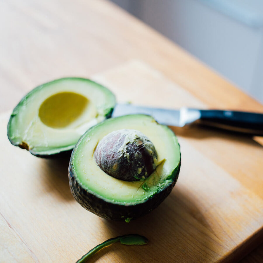 Aguacate Hass de Bionta recién cortado sobre una tabla de madera con un cuchillo al lado